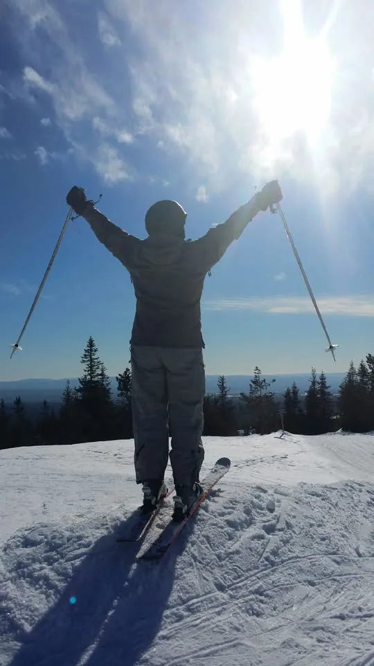 En person står på ski og nyter solen