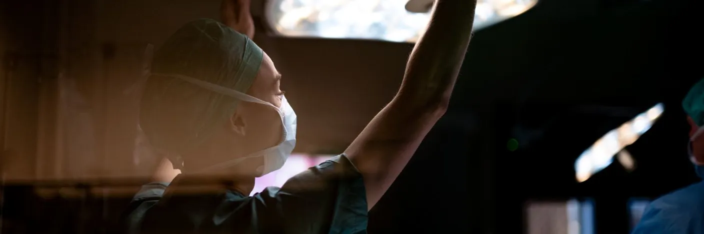 Operasjonssykepleier strekker seg mot operasjonslampe