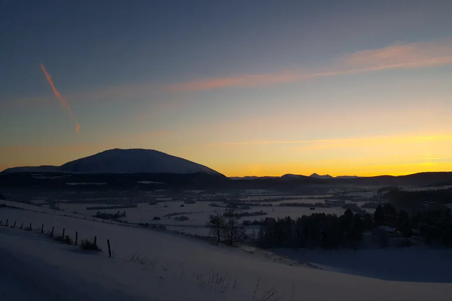 Landskap i Fjellregionen med Tronfjell i det fjerne og solnedgang.