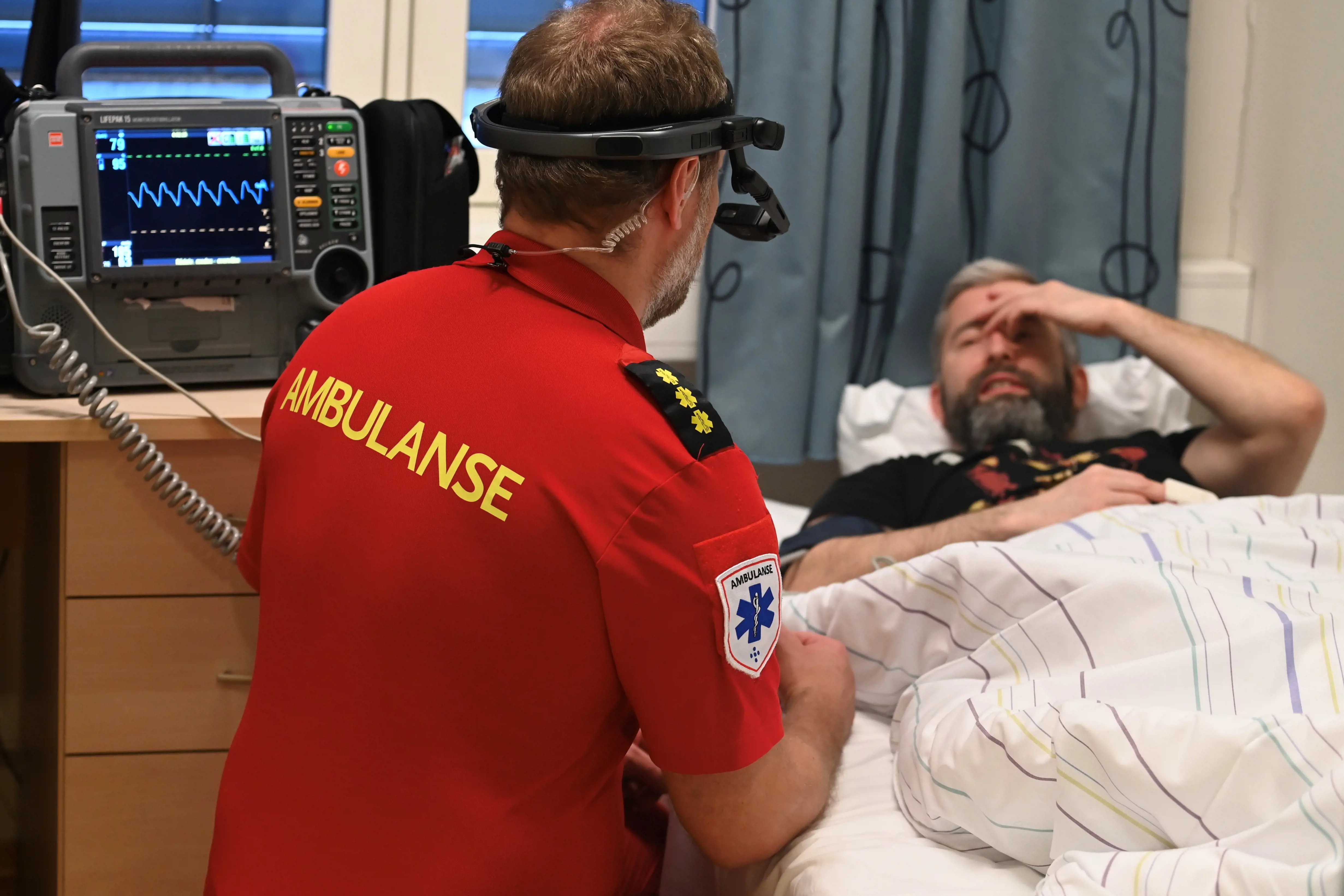 Ambulansearbeider med hodekamera i interaksjon med pasient.