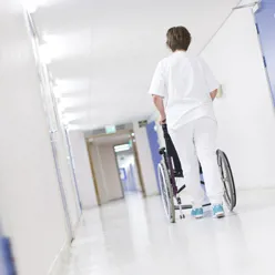 Helsepersonell triller rullestol i sykehuskorridor, illustrasjonsbilde