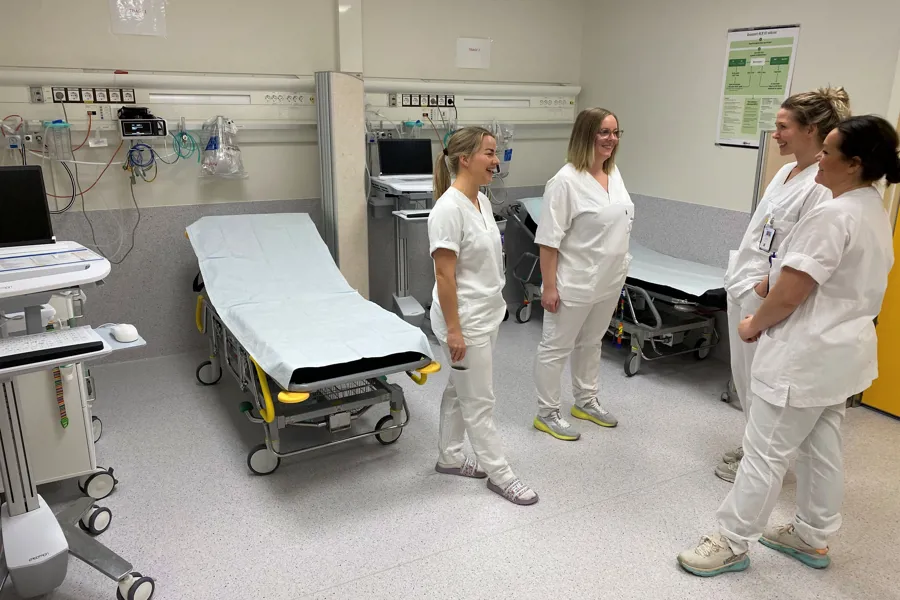 Fire blide sykepleiere snakker med hverandre i moderniserte lokaler.