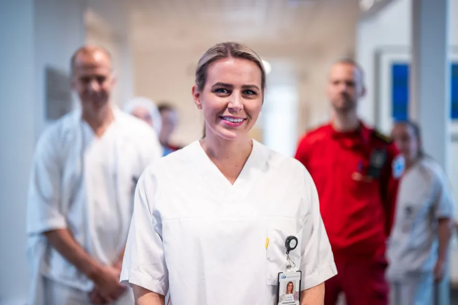Sykepleier i forgrunn med andre yrkesgrupper i bakgrunn, portrett