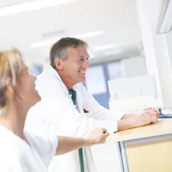 Helsepersonell i munter passiar ved en skranke på sykehuset, illustrasjonsbilde